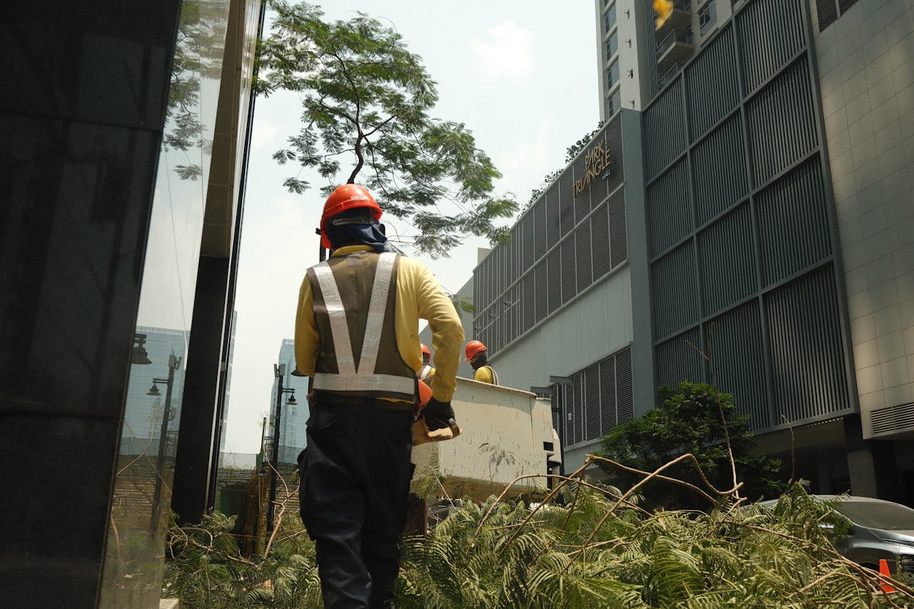 Construction workers in safety gear clearing debris on a sunny day in a Philippine city.
